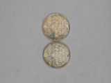 two coins sitting side by side on top of a white surface
