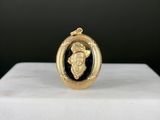 une image représentant un pendentif doré et noir orné d'un visage de femme