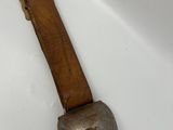 a metal object with a wooden handle on a white surface