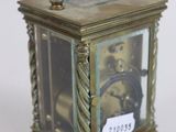 a small brass clock with a rope on the handle