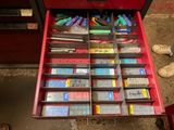 un tiroir rouge contenant de nombreux stylos et crayons de différentes couleurs