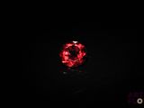 a close up of a red stone on a black surface