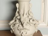 a white vase sitting on a table in front of a blue wall