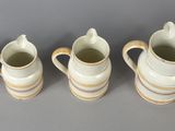 five white vases lined up on a gray wall
