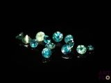 un gros plan sur un ensemble de diamants bleus et verts posés sur une surface noire