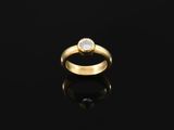 a gold ring with a single diamond on a black surface