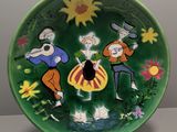 une assiette verte sur laquelle est représenté un groupe de personnes