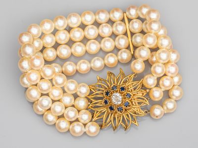 une photo d'un bracelet en or et perles orné d'une broche en forme de fleur