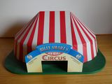 un chapiteau de cirque miniature posé sur une table, avec une pancarte dessus