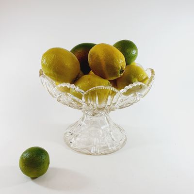 a glass bowl filled with lemons and limes on a table