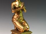 statue en bronze représentant une femme assise sur un socle, les mains croisées