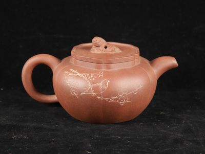 a brown teapot with a bird on it sitting on a black surface