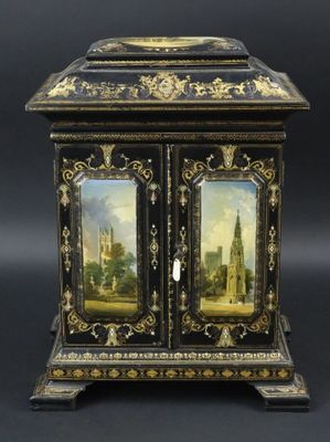 un meuble ancien peint en noir et or, orné d'un tableau sur la porte