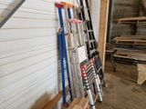 a pile of ladders leaning against a wall in a garage