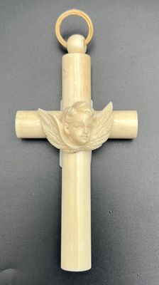 an ivory cross with a angel on it and a gold ring around it
