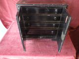 a small black chest of drawers on a pink chair