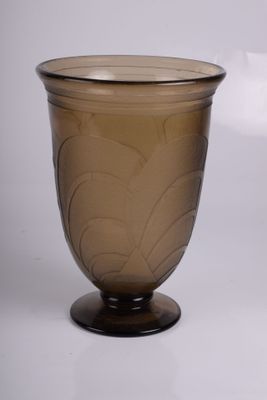 un vase en verre brun muni d'un couvercle, posé sur une surface blanche