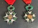 two medals on a table with a red ribbon and a green ribbon