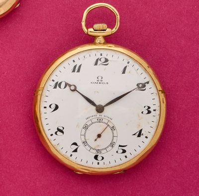 une montre de poche en or posée sur une surface rose