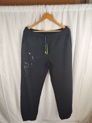 Le pantalon Nike est suspendu à un cintre devant un rideau blanc.