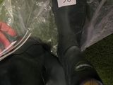 a person sitting on the grass with a pair of black rain boots