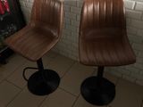 pair of brown leather bar stools in front of a soda cooler