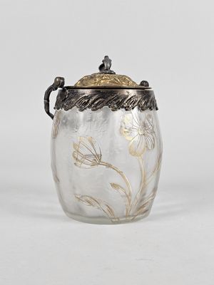 an antique silver and glass jar with a floral design on the lid