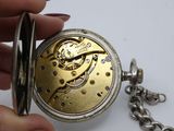 a person holding a pocket watch with a chain around it