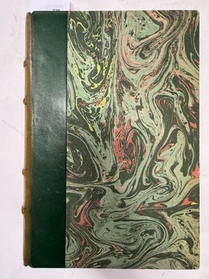un vieux livre à la couverture verte posé sur une table blanche