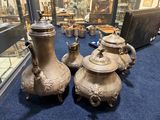 trois vases posés sur un tapis bleu devant une vitrine