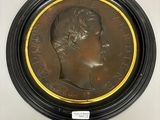 un médaillon en bronze représentant un homme coiffé d'une couronne