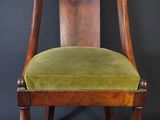 an old chair with a green velvet seat on a black background