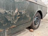 a dirty car that is parked on the side of the street