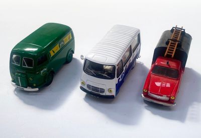 trois petites voitures disposées côte à côte sur une surface blanche