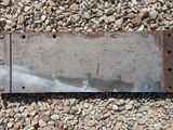 a rusted metal sign sitting on a pile of rocks