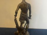 bronze statue of a man holding a sword and standing on a blue surface