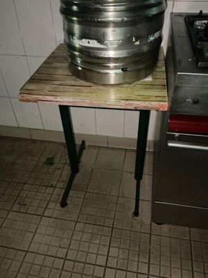 stainless steel keg sitting on top of a wooden table next to a stove