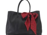 a black handbag with a red bow on the front