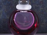 a purple glass bottle with a white top on a table
