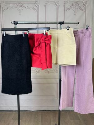 three different colored skirts hanging on a clothes rack in a room