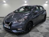 une Nissan Versa grise garée dans une pièce au sol à carreaux