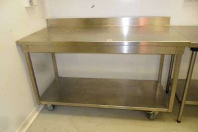 a stainless steel table with two stools in the corner
