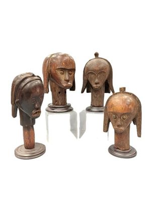 four wooden head sculptures of different shapes and sizes on a white surface