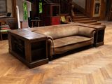 a brown leather couch sitting on a parquet floor