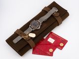 a brown case with a watch on it and a red card