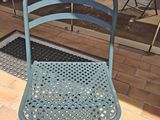 a blue metal chair sitting on a brick patio