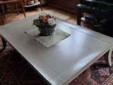 une table basse blanche sur laquelle est posé un vase de fleurs