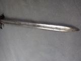 an old sword with a metal handle on a gray surface