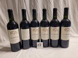six bottles of red wine lined up in a row on a table