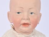 a small doll of a baby that is wearing a white shirt